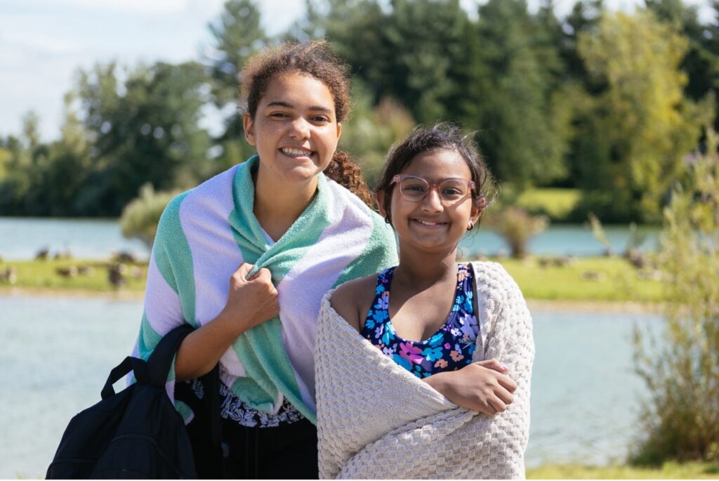sophie and a friend in front of the lake at camp