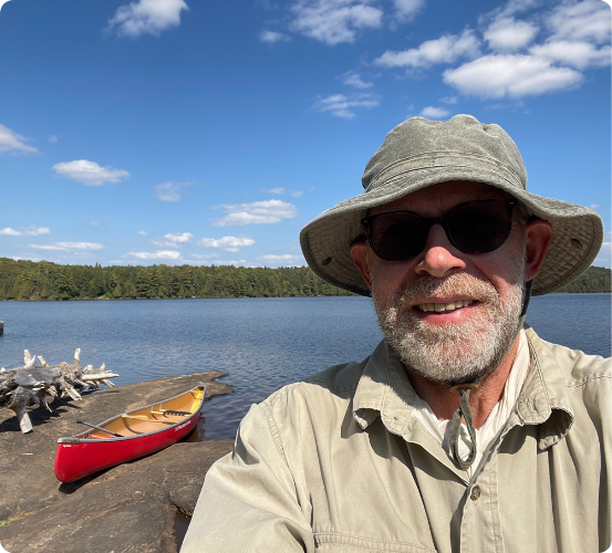 michael on a beach with canoe in background on sunny day