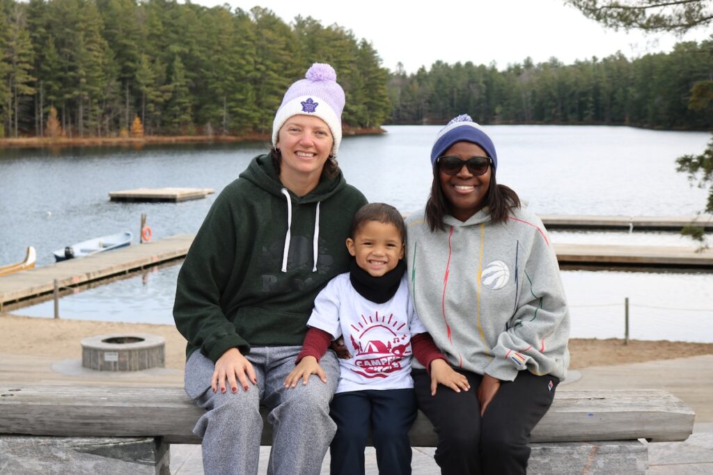 carter with family at camp with lake and trees in background