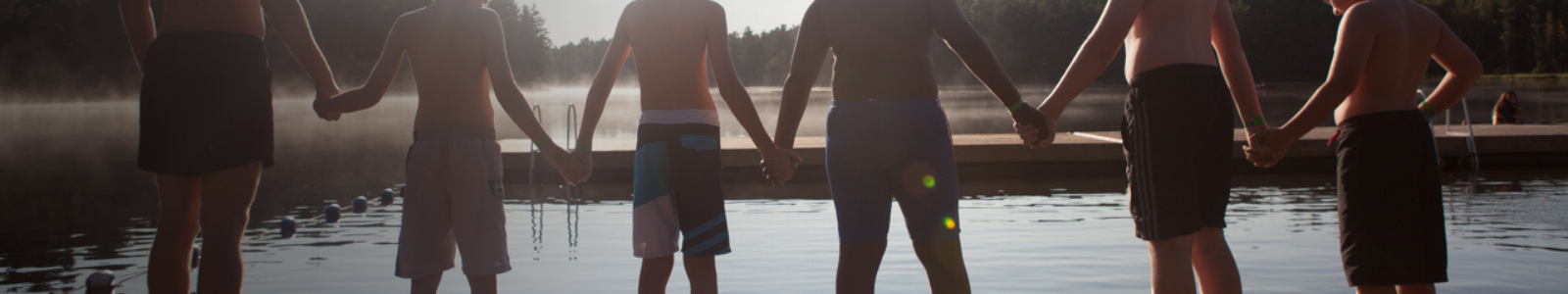campers holding hands on a dock on the lake at camp
