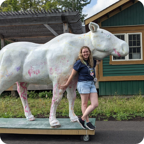 amanda standing next to white moose sculpture at camp