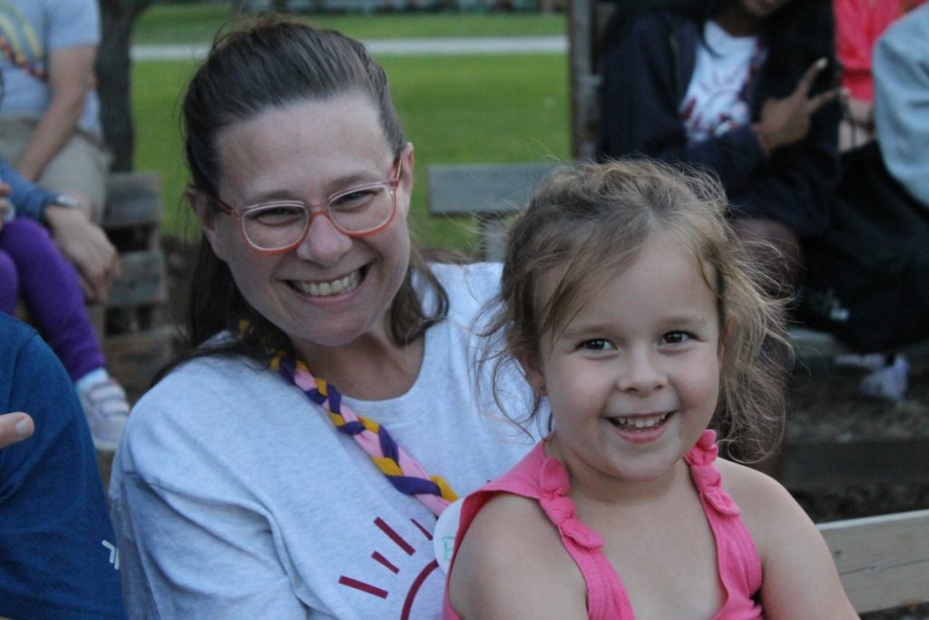 brooke with daughter on lap on a bench outside at camp